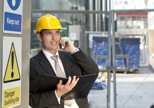 A supervisor talks on his cellphone while reviewing plans