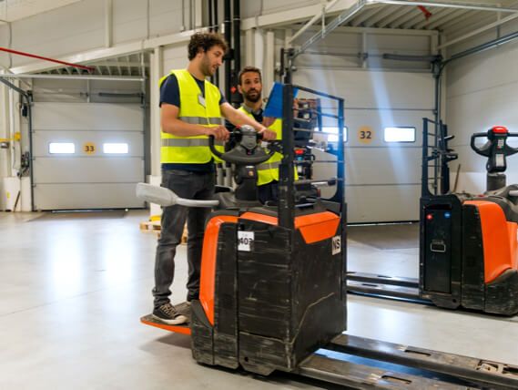 A worker leans how to operate a forklift