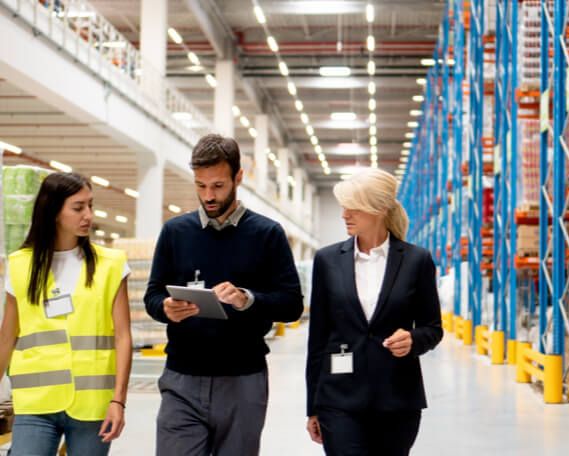 A manager, supervisor, and member of joint health and safety committee walk through a warehouse