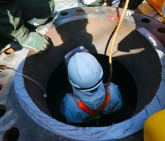 a worker with a harness is lowered into a confined space