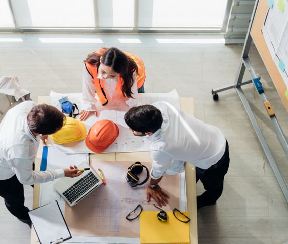 Three construction workers in office clothing going over documents on a table