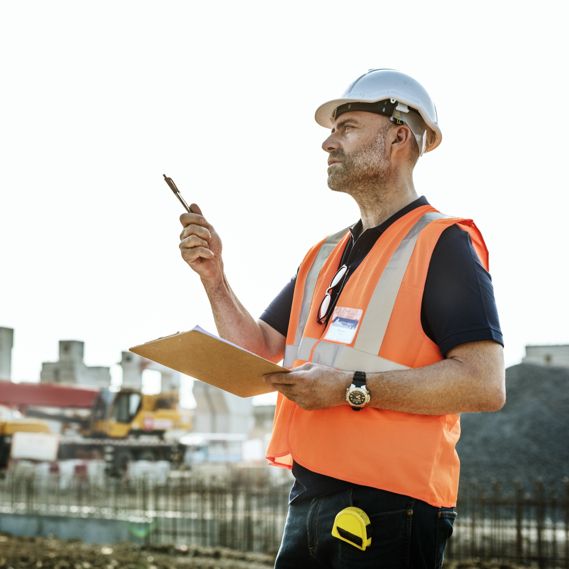 A supervisor takes notes of safety measures on a consturction site