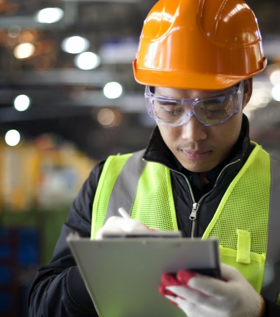 A member of a health and safety committee takes notes on a clipboard