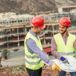 two male construction workers talking about the project timeline to ensure productivity is optimized