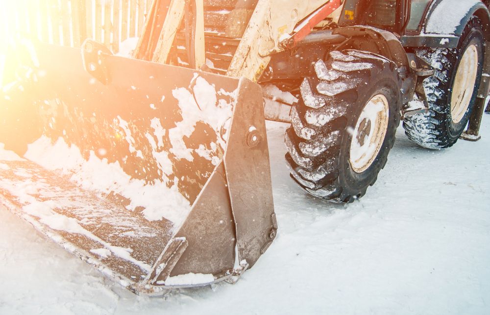 worker operating snowplow in winter