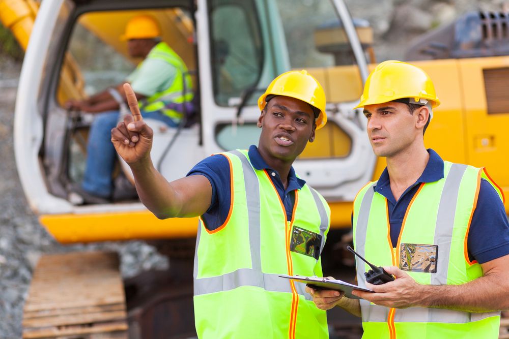 two construction workers standing next to each other talking about the project.