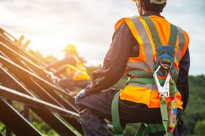 a construction worker on a building's roof wearing proper fall protection equipment