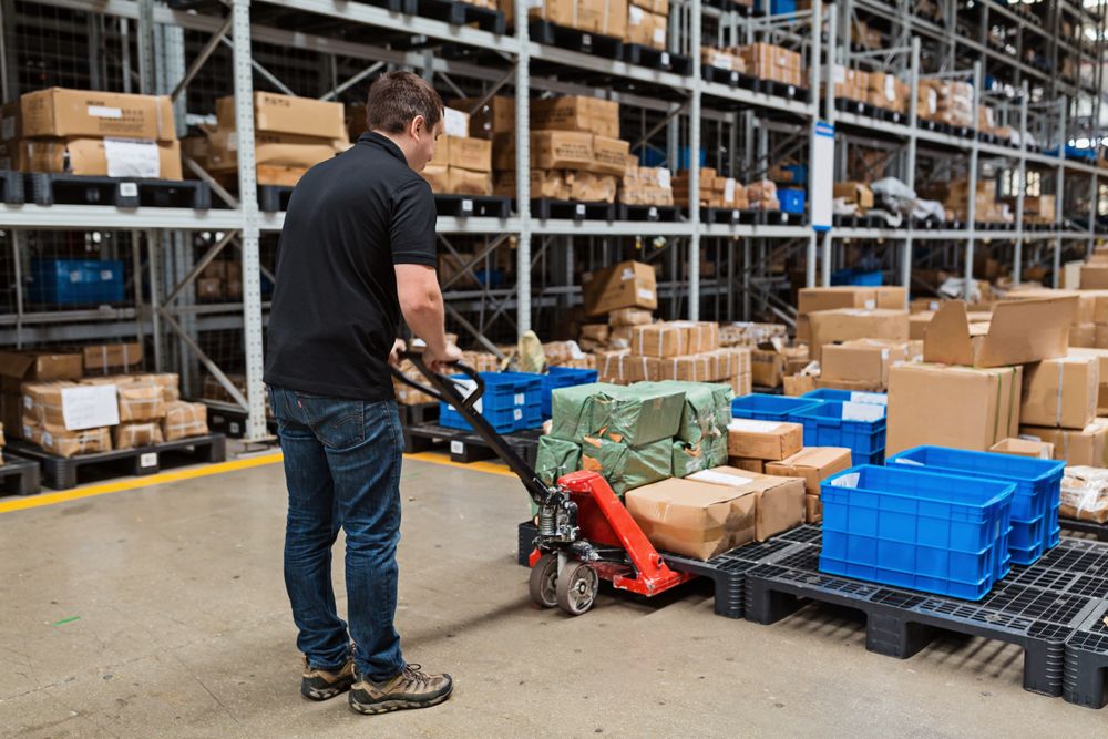 warehouse worker using equipment to handle a pallet of items in a warehouse