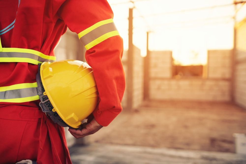 worker in ppe holds helmet at job site