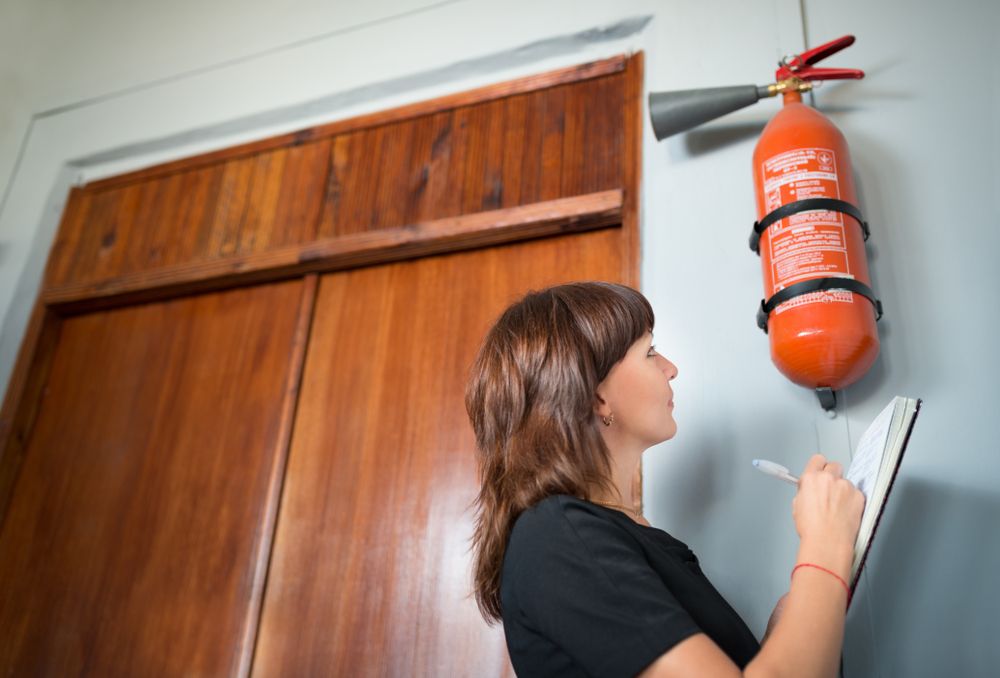 woman inspects fire extinguisher in workplace safety review