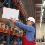 A man safely lifting a box onto a shelf in a warehouse