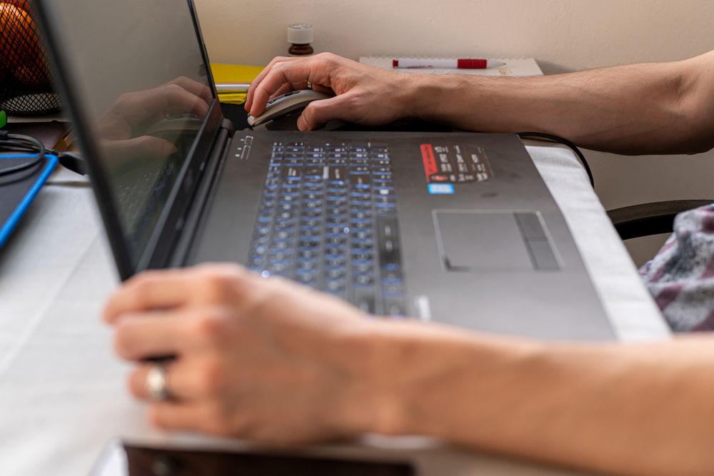 a side view of a laptop with someone's hands resting on each side