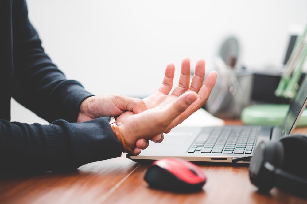 employee massaging their hand due to pain from a repetitive stress