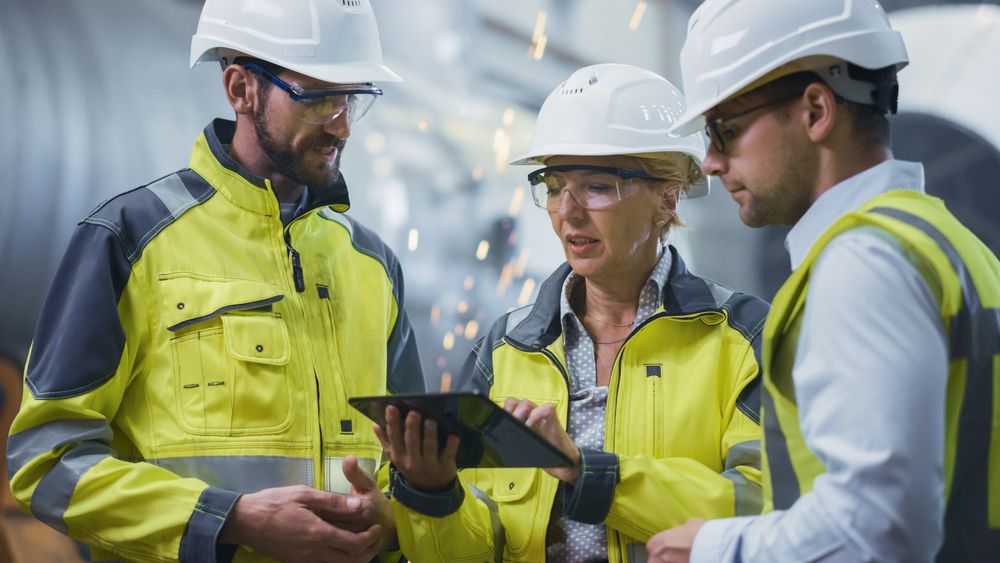 3 construction engineers working together on a device reviewing the safety program