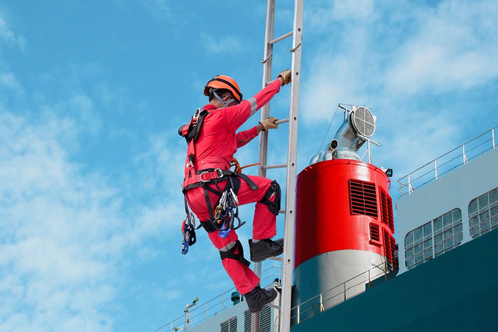 employee working at heights wearing the proper safety shoes for good grip on the ladder.