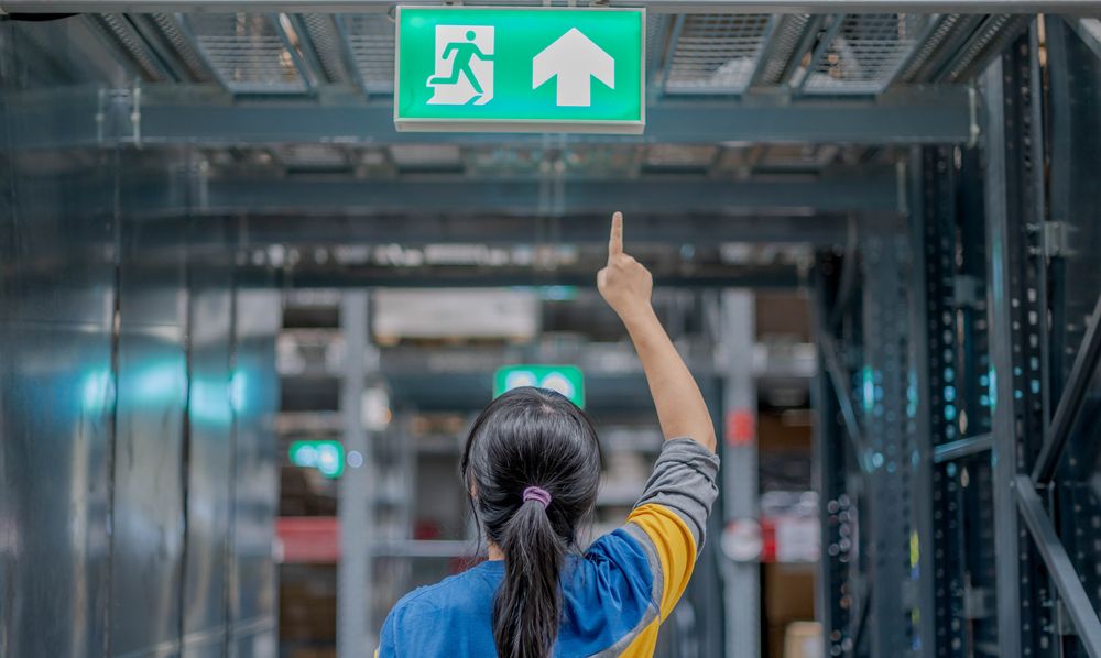 a female employee pointing at the emergency exit sign