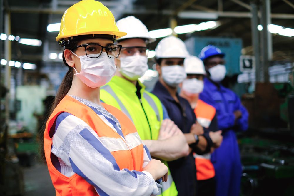 a line up of warehouse workers standing with their arms crossed and wearing masks