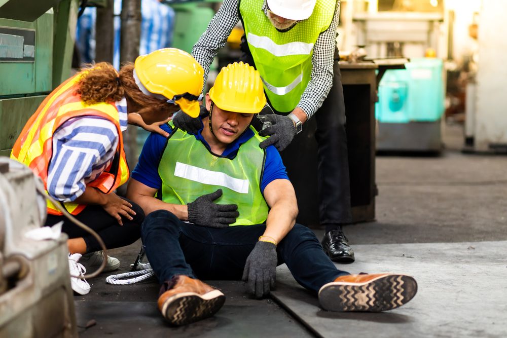 a warehouse worker suffering from an injury while two co-workers assess the situation
