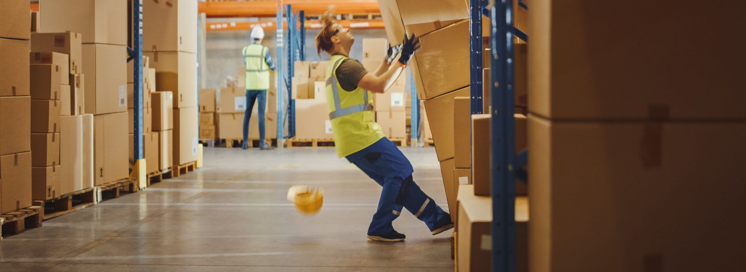 a warehouse worker grabbing boxes improperly which has resulted on them falling