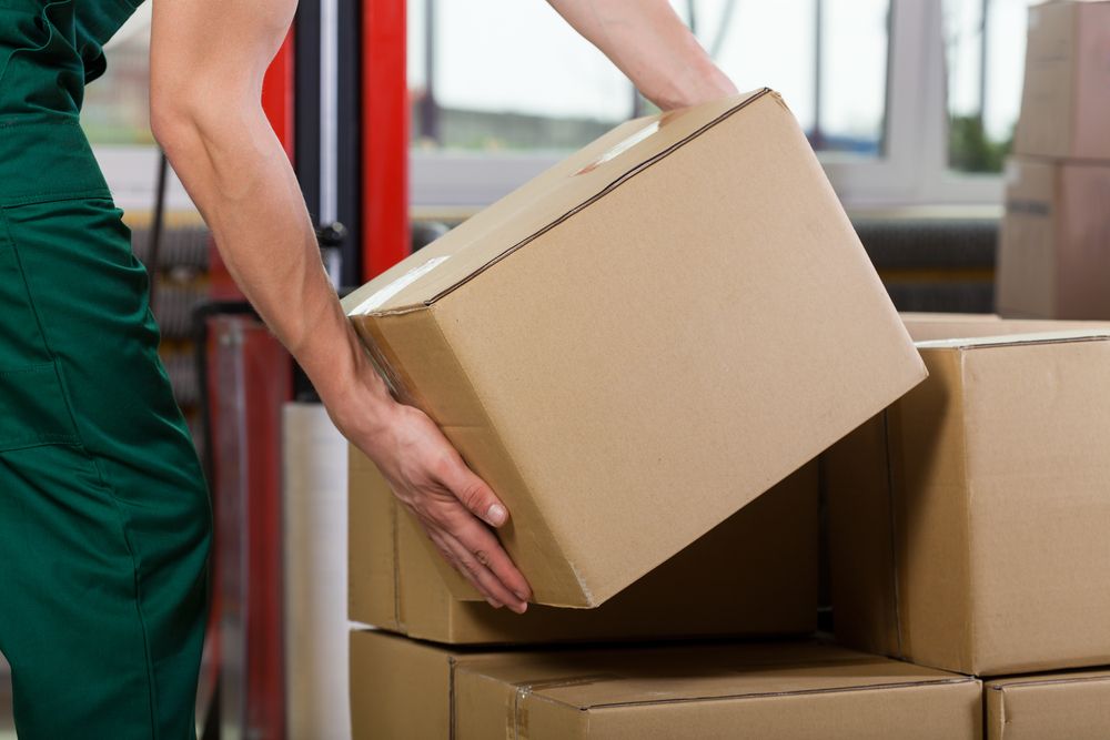 warehouse employee ergonomically lifting a box that does not exceed the weight limit set by his employer