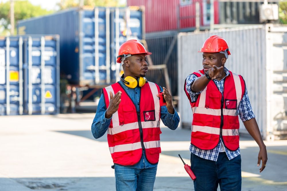 a senior employee showing a new employee the proper safety measures in place for receiving dangerous goods