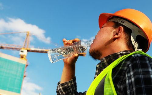 worker drinks water stays hydrated while outside in summer heat