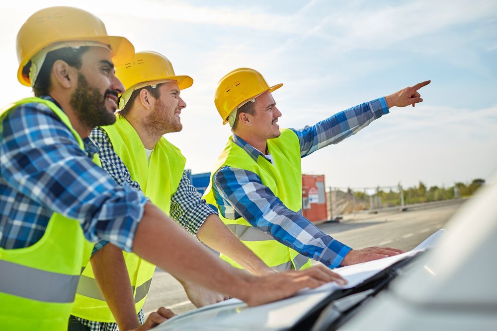 three construction workers standing together to discuss the project safety plan