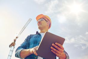 a construction worker looks around for potential safety risks while holding a clipboard
