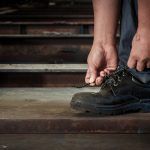 a worker wearing safety boots and tying the laces