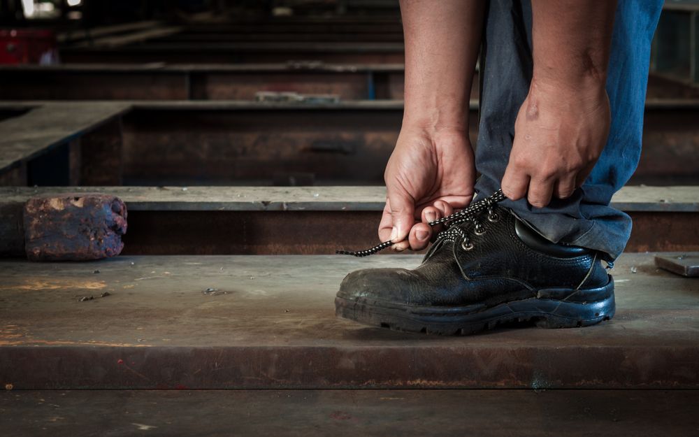 a worker wearing safety boots and tying the laces