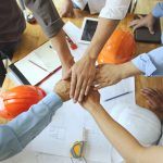 workers with their hands in a pile representing teamwork