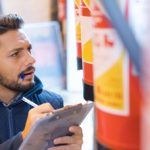 A worker takes notes expiration dates for fire extinguishers