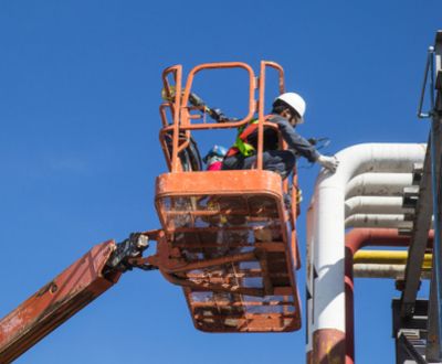 Men on boom lift work on pipes at height safely
