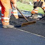 a construction worker using equipment to flatten asphalt on the road