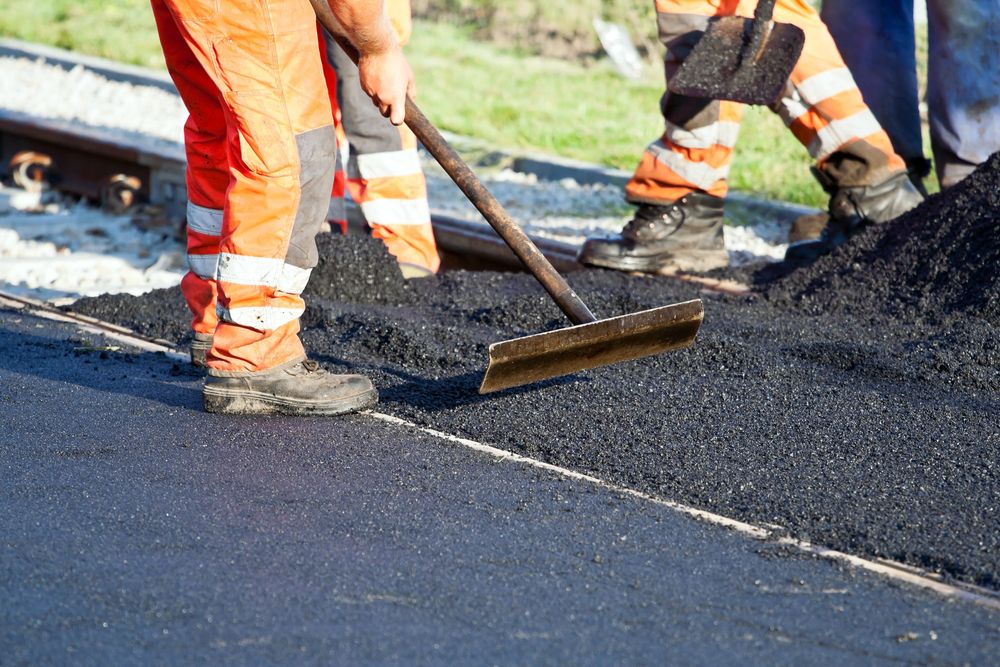 a construction worker using equipment to flatten asphalt on the road