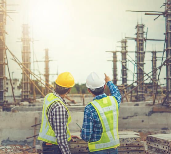 two construction site workers surveying their job site