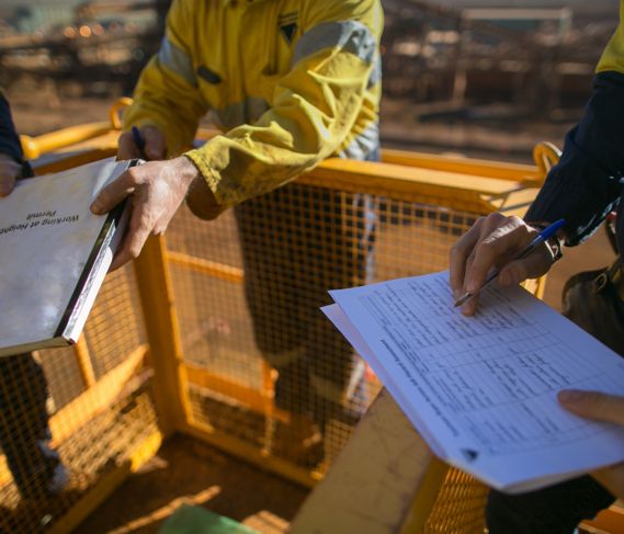 A construction worker hands a binder to a coworker
