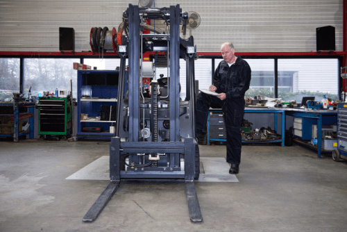 a mechnaic performing routine maintenance on a forklift.