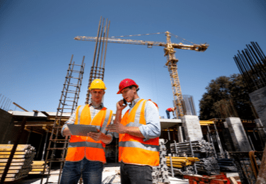 Two workers review plans at a construction site