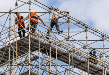 Construction workers safely work on scaffolding